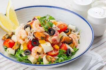 Close up of Italian mixed seafood salad. Insalata di mare. Calamari, shrimp, clams, tomatoes, bell pepper, parsley and olives..
