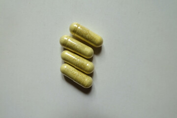 View of four yellowish green capsules of quercetin dietary supplement from above