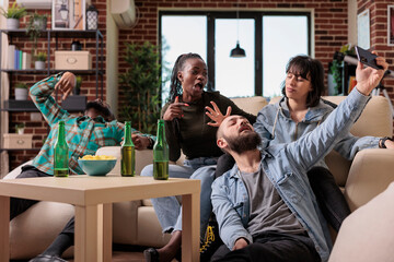 Smiling friends having fun with photos taken on smartphone camera, creating memories together at...