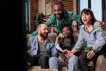 Cheerful men and women feeling happy about winning video games, having fun together at house gathering. People celebrating win and victory, playing with virtual reality glasses.