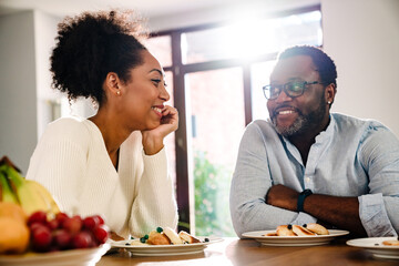 African american woman and man sitting by table while having breakfast
