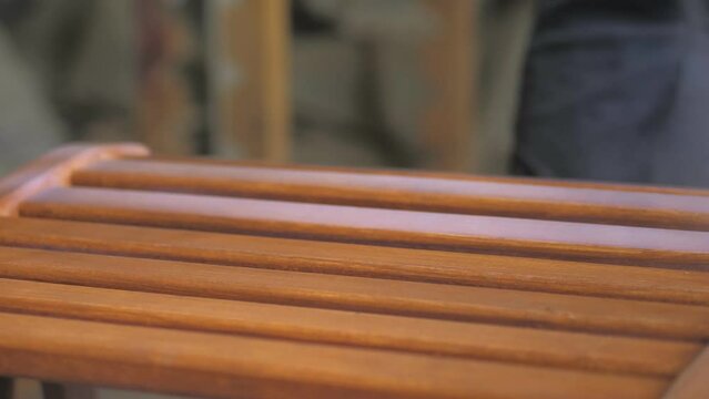 Carpenter-men wearing gloves, apply varnish or primer with compressed air on a wooden surface. Painting of wooden products with a spray gun in a carpentry workshop.Paint and varnish coating.Close-up