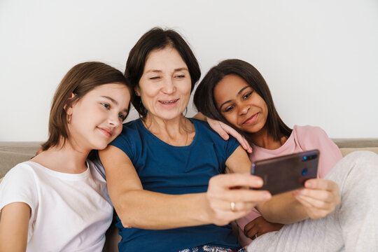White woman and her daughters taking selfie photo while resting on couch