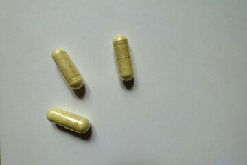 View of three yellowish green capsules of quercetin dietary supplement from above