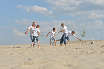Portrait of family playing football on a beach in summer day