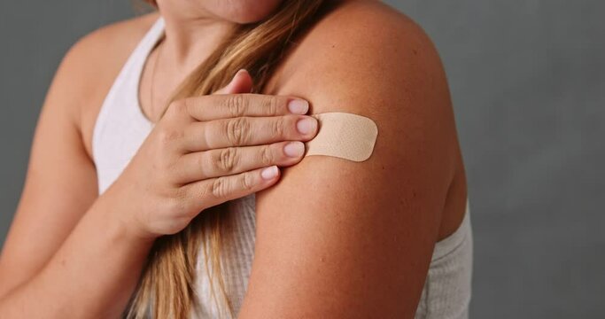 Young Caucasian female touching her band aid