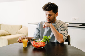 Young indian man with orange juice and fresh salad