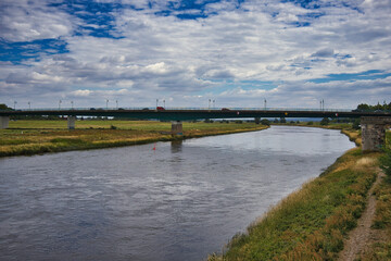 Fototapeta premium Blick auf die moderne Elbebrücke (Straßenbrücke) über den Flusslauf unter ausdrucksstarkem Wolkenhimmel bei Torgau, Sachsen, Deutschland