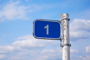 Road sign 1 km against the blue sky with white clouds