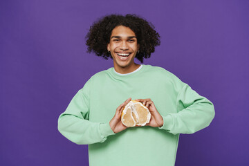Young smiling happy latin man holing pomelo on his chest