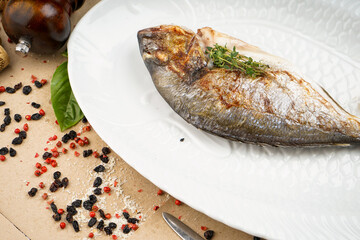 baked fish on a white plate with lemon macro photo
