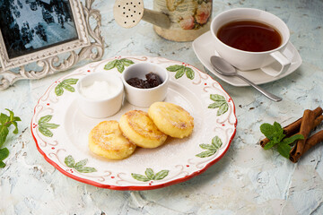 breakfast sweet cheesecakes in a plate on a background with tea
