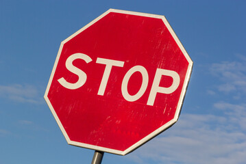 Red Stop Sign with Blue Sky and Clouds Background