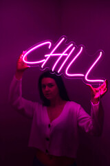 Beautiful girl with neon signs. Pink neon sign chill. Trendy style. Neon sign. Custom neon. Home decor.