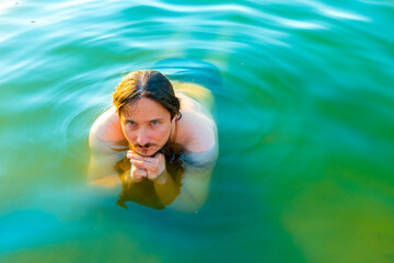  caucasian man floating in a swimming lake with blue water