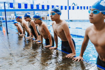 latin young man swimmer athlete wearing cap and goggles in a swimming training holding On Starting...