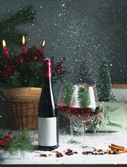 Christmas still life with red wine bottle and wineglasses on table with seasonal decoration,...