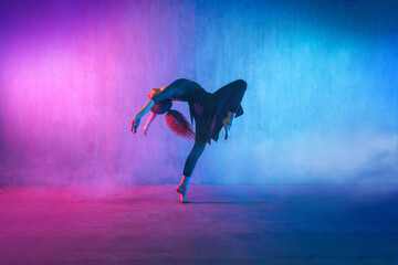 Modern dance girl dancer dancing in neon light doing gymnastic exercises in studio, copy space. - obrazy, fototapety, plakaty