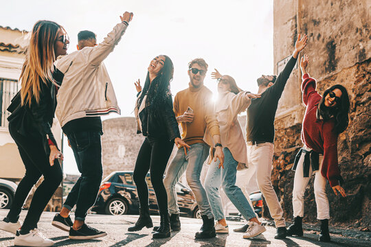 group of multiethnic happy friends having fun on weekend dancing together in the streets - joyful multiracial young people lifestyle concept