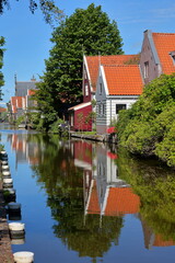 Fototapeta na wymiar Colorful and historic house facades in De Rijp, Alkmaar, North Holland, Netherlands, reflected on a canal. De Rijp is known for its rijksmonuments
