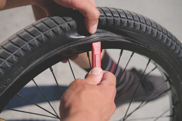 mechanic removes the tire from the bicycle wheel by tire lever during replacement of the inner tube...