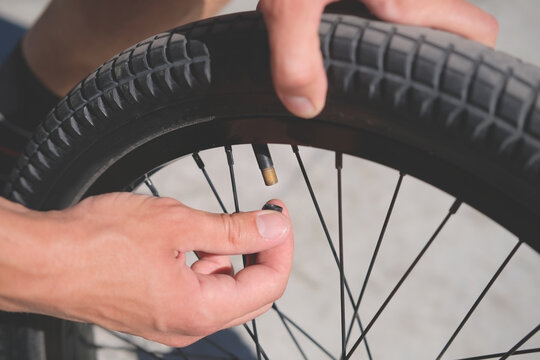 person with wheel attaches a cap to the nipple while repairing bicycle close up