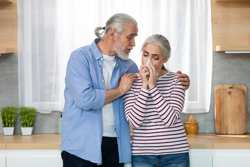 Caring Senior Man Comforting His Crying Wife In Kitchen At Home
