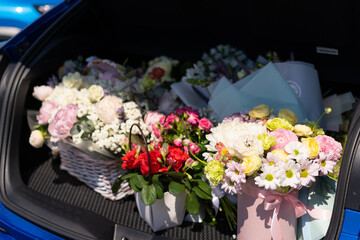 Bouquets of beautiful bright multi-colored flowers in the trunk of a car, a gift for a wedding, for a birthday