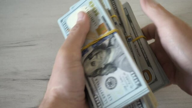 4K view of male hands stacking stacks of dollar bills.