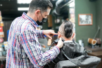 An adult man with a mohawk in a barbershop. The master