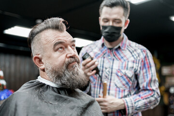 Barbershop. The master works with the beard of an adult man