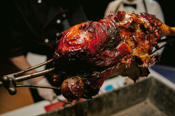 A cook in a restaurant prepares an appetizing roast lamb with a crispy crust on a spit. Leg lamb,...