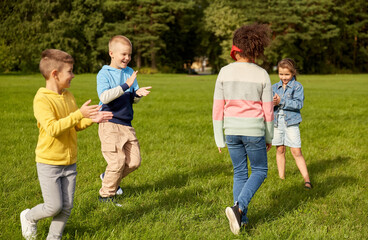 Fototapeta premium childhood, leisure and people concept - group of happy children playing tag game and running at park