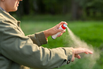 health care, protection and people concept - woman spraying insect repellent or bug spray to her hand at park