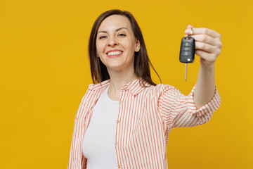 Young happy smiling cool fun woman she 30s wear striped shirt white t-shirt hold in hand give car keys fob keyless system isolated on plain yellow background studio portrait. People lifestyle concept.