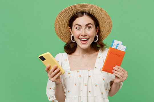 Traveler tourist woman she in summer clothes hat hold pasport ticket mobile cell phone isolated on pastel plain green background Passenger travel abroad on weekends getaway Air flight journey concept.