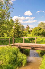 Fototapeta na wymiar Summer landscape with a wooden chapel in the forest and a wooden bridge over the river