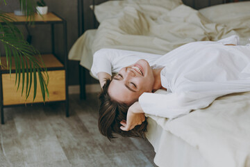 Side view calm fun young woman wear white shirt pajama she lying in bed close eyes rest relax spend...