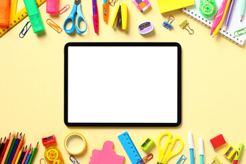 Digital tablet with blank white screen and frame of colorful school supplies on yellow background. Online school, distance e-learning concept. Flat lay, top view, copy space