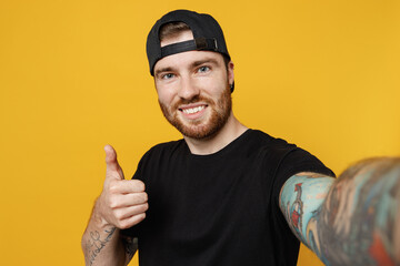 Close up young bearded tattooed man 20s he wears casual black t-shirt cap doing selfie shot pov on...