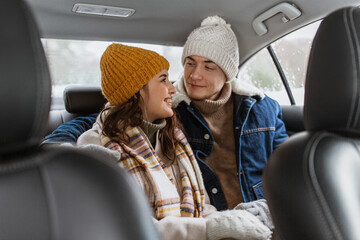 people, love and leisure concept - happy smiling couple hugging on car back seat in winter
