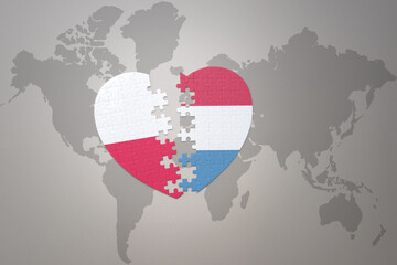 puzzle heart with the national flag of luxembourg and poland on a world map background.Concept.