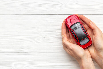Toy car in hands, top view. Car insurance or driving safety concept - obrazy, fototapety, plakaty
