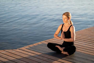 Fototapeta na wymiar Morning Meditation. Calm Middle Aged Woman Meditating Outdoors On Wooden Pier
