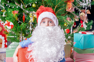 Big white beard on a little boy posing as santa claus.