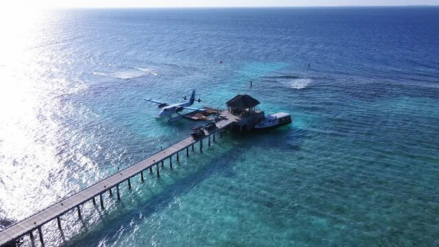 Static Drone shot of Docked Seaplane to a wooden Pier on transparent blue water, Vakkaru, Maldives. Seaplane transporting passengers to small islands from Male Airport