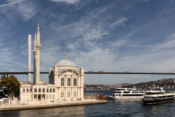 Fototapeta na wymiar View of cruise tour boats on Bosphorus, historical Ortakoy mosque and bridge in Istanbul. It is a sunny summer day.