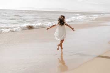 Fototapeta na wymiar Carefree girl running near waving sea