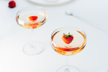 Cocktail drinks in cocktails glasses with fresh strawberry on the white table. Light drink for summer party. Selective focus, copy space.