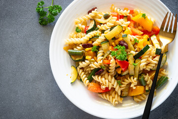 Vegan pasta with fried vegetables. Top view on stone table.